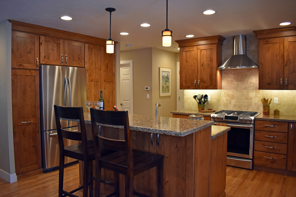 Example of a mid-sized eclectic l-shaped medium tone wood floor and brown floor eat-in kitchen design in Denver with brown cabinets, beige backsplash, stainless steel appliances, an island, an undermount sink and shaker cabinets