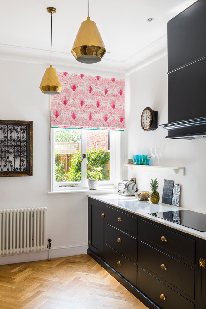 This is an example of a classic single-wall kitchen in London with flat-panel cabinets and light hardwood flooring.