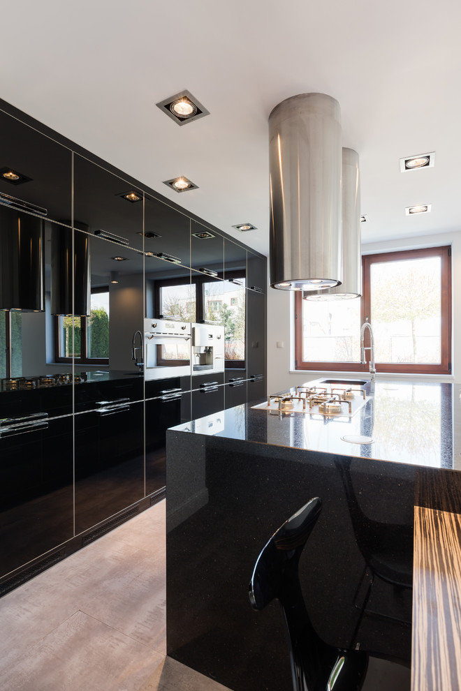 Large contemporary single-wall kitchen/diner in Los Angeles with a built-in sink, flat-panel cabinets, black cabinets, black splashback, stainless steel appliances, cement flooring, an island and brown floors.
