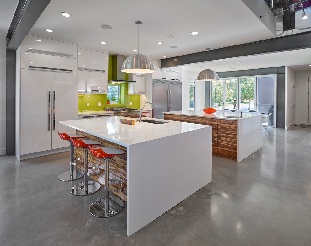 Bild på ett mellanstort funkis vit vitt kök, med en undermonterad diskho, släta luckor, bänkskiva i kvarts, grönt stänkskydd, glaspanel som stänkskydd, betonggolv, flera köksöar, grått golv, vita skåp och rostfria vitvaror