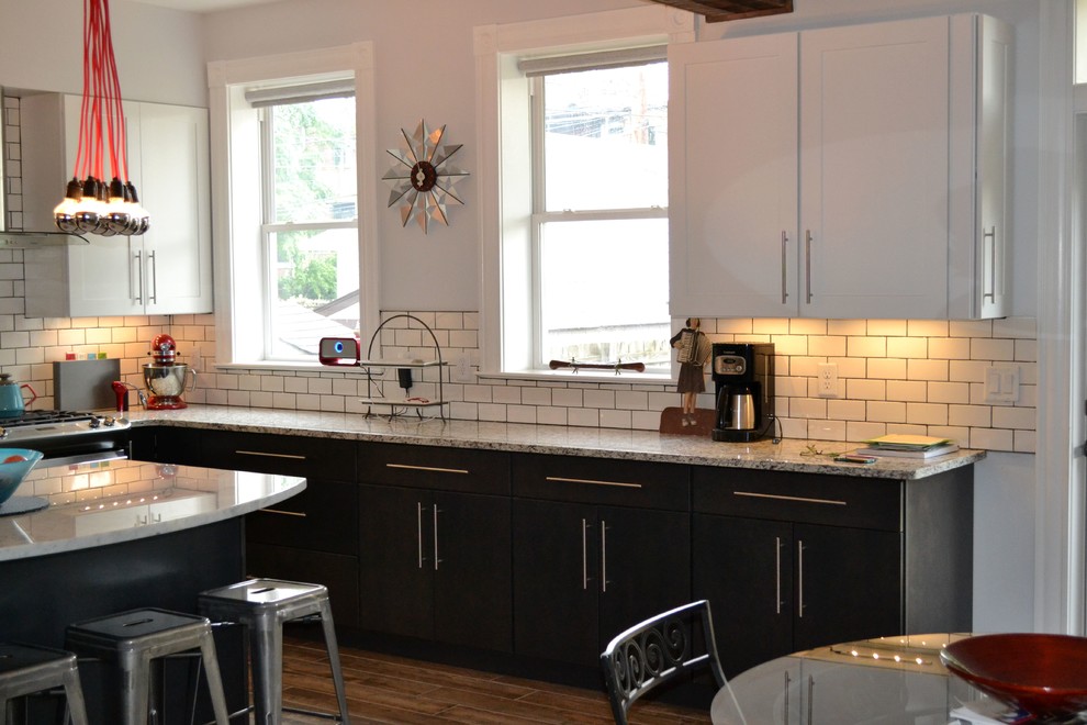 Modelo de cocina urbana, grande, con fregadero bajoencimera, salpicadero de azulejos tipo metro, electrodomésticos de acero inoxidable, suelo de baldosas de porcelana y una isla