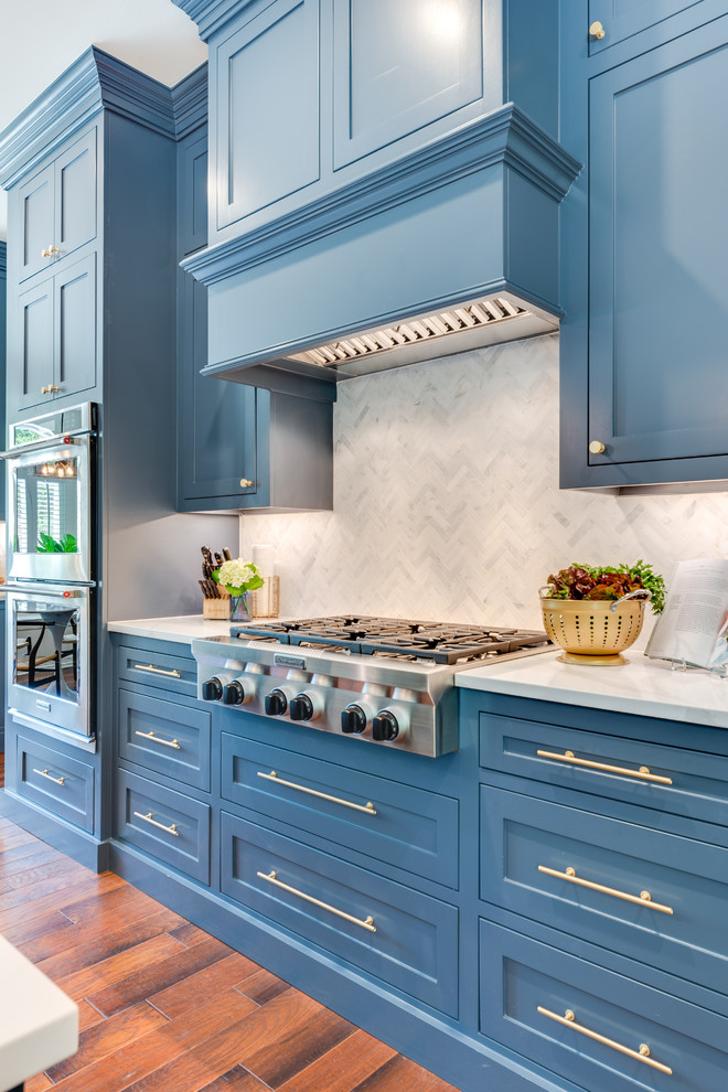 Exempel på ett stort klassiskt vit vitt kök, med en undermonterad diskho, skåp i shakerstil, blå skåp, marmorbänkskiva, grått stänkskydd, stänkskydd i marmor, rostfria vitvaror, mellanmörkt trägolv, en köksö och brunt golv
