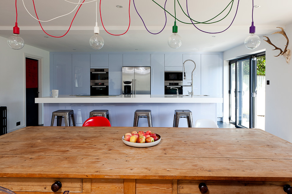 Zweizeilige Moderne Wohnküche mit flächenbündigen Schrankfronten, blauen Schränken und Küchengeräten aus Edelstahl in London