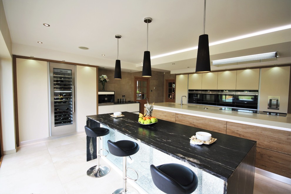 Large contemporary kitchen in Essex with flat-panel cabinets, black appliances, porcelain flooring and multiple islands.