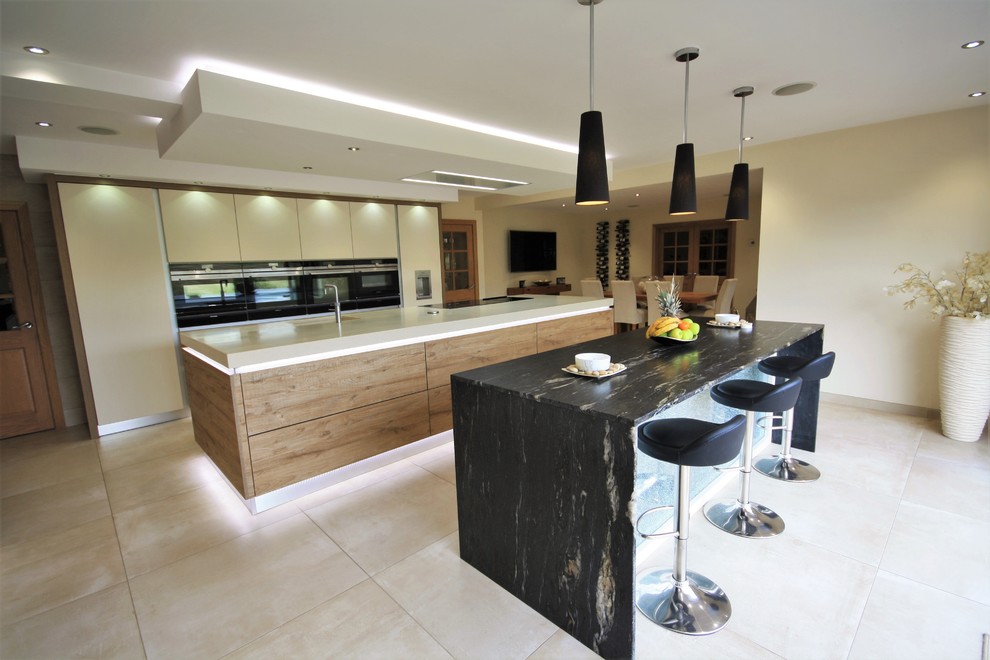 Immagine di una grande cucina minimal con ante lisce, elettrodomestici neri, pavimento in gres porcellanato e 2 o più isole