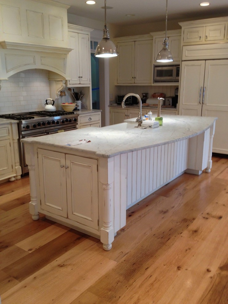 Example of a mountain style light wood floor eat-in kitchen design in DC Metro with a farmhouse sink, flat-panel cabinets, white cabinets, laminate countertops, white backsplash, porcelain backsplash, stainless steel appliances and an island