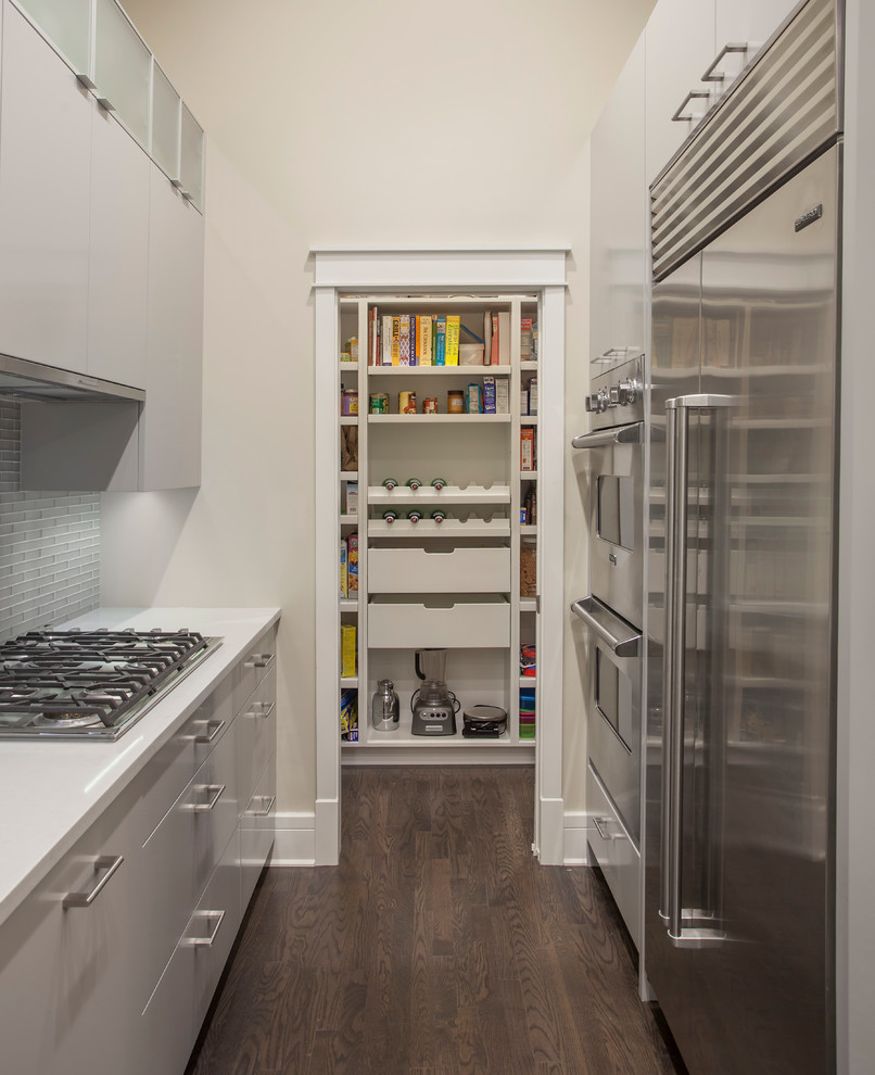 Bild på ett mellanstort funkis kök, med en undermonterad diskho, släta luckor, grå skåp, bänkskiva i kvarts, grått stänkskydd, stänkskydd i glaskakel, rostfria vitvaror, mörkt trägolv och en halv köksö