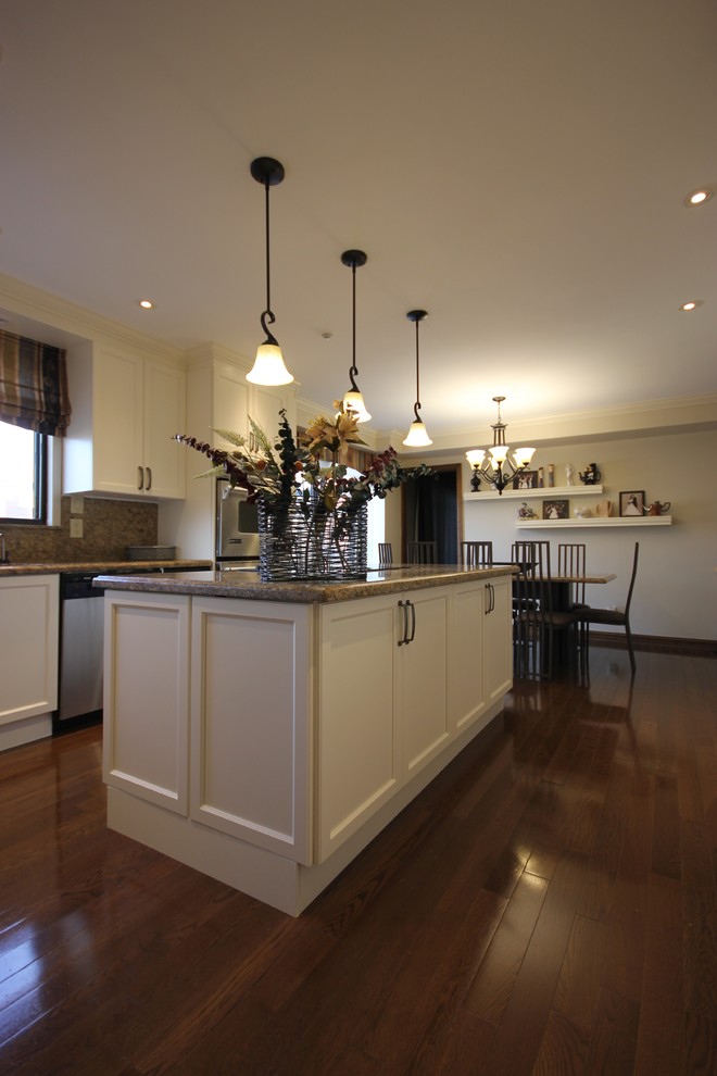 Exempel på ett stort klassiskt kök, med en undermonterad diskho, luckor med infälld panel, vita skåp, granitbänkskiva, brunt stänkskydd, stänkskydd i sten, rostfria vitvaror, mörkt trägolv och en köksö