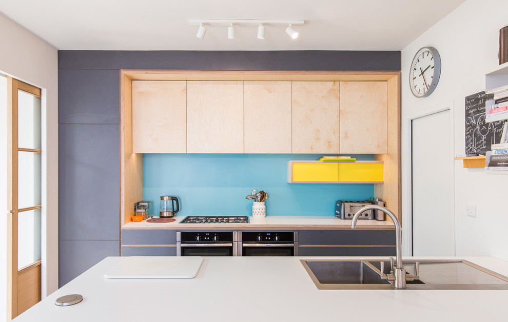 Small contemporary single-wall kitchen/diner in Sussex with a double-bowl sink, flat-panel cabinets, blue cabinets, blue splashback, stainless steel appliances and an island.