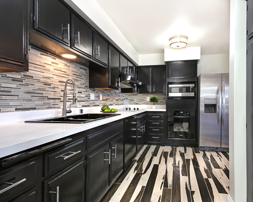 Example of a transitional l-shaped eat-in kitchen design in Los Angeles with black cabinets, quartz countertops and mosaic tile backsplash