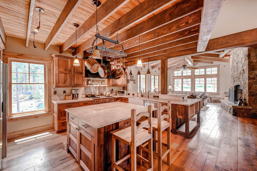 Photo of a large rustic l-shaped open plan kitchen in Denver with a belfast sink, recessed-panel cabinets, medium wood cabinets, stainless steel appliances, an island, medium hardwood flooring and brown floors.