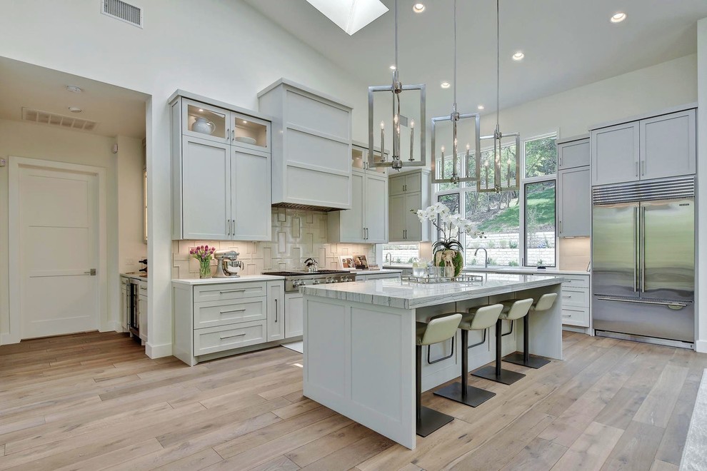 Eat-in kitchen - large transitional eat-in kitchen idea in Austin with an undermount sink, shaker cabinets, beige backsplash, ceramic backsplash, stainless steel appliances, an island, granite countertops and gray cabinets
