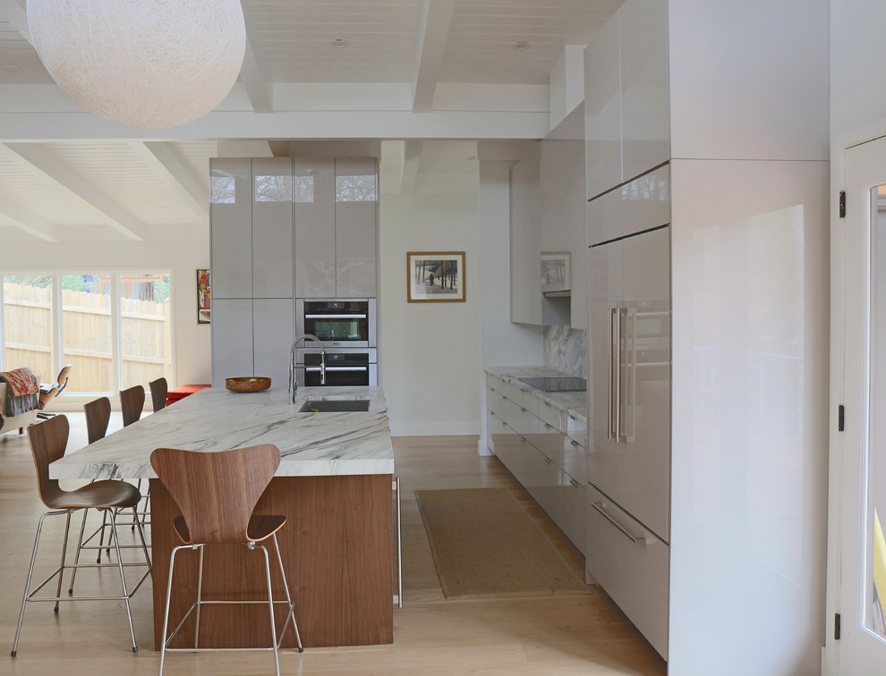 Idéer för att renovera ett mellanstort funkis kök, med en undermonterad diskho, släta luckor, grå skåp, integrerade vitvaror, ljust trägolv, en köksö, marmorbänkskiva, vitt stänkskydd, stänkskydd i marmor och brunt golv