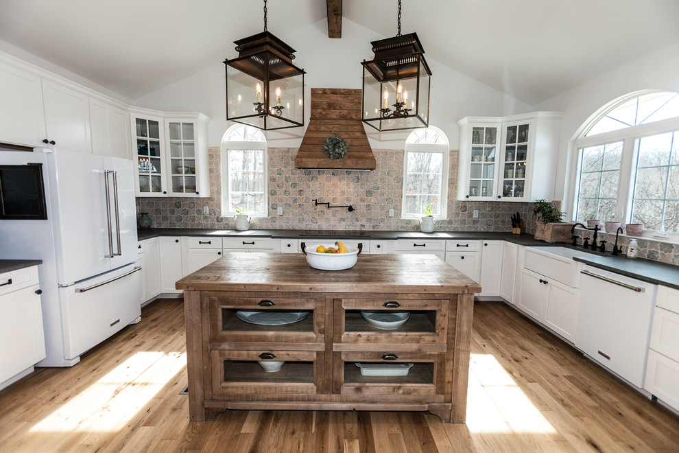 Immagine di un cucina con isola centrale country con top in granito, paraspruzzi con piastrelle in ceramica, pavimento in legno massello medio e top nero