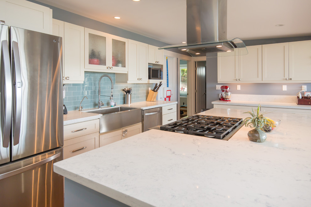 Example of a large transitional l-shaped light wood floor open concept kitchen design in Hawaii with a farmhouse sink, shaker cabinets, white cabinets, quartz countertops, blue backsplash, subway tile backsplash, stainless steel appliances and an island