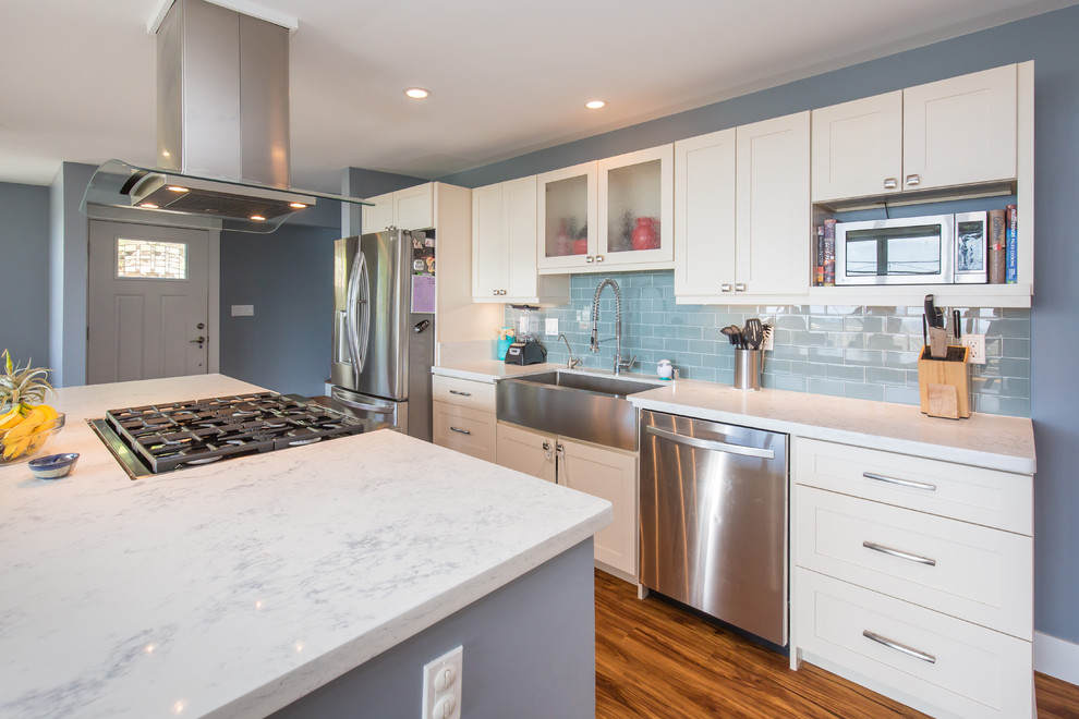 Open concept kitchen - large transitional l-shaped light wood floor open concept kitchen idea in Hawaii with a farmhouse sink, shaker cabinets, white cabinets, quartz countertops, blue backsplash, subway tile backsplash, stainless steel appliances and an island