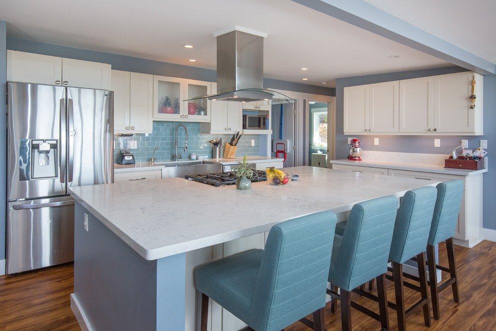 Example of a large transitional l-shaped light wood floor open concept kitchen design in Hawaii with a farmhouse sink, shaker cabinets, white cabinets, quartz countertops, blue backsplash, subway tile backsplash, stainless steel appliances and an island