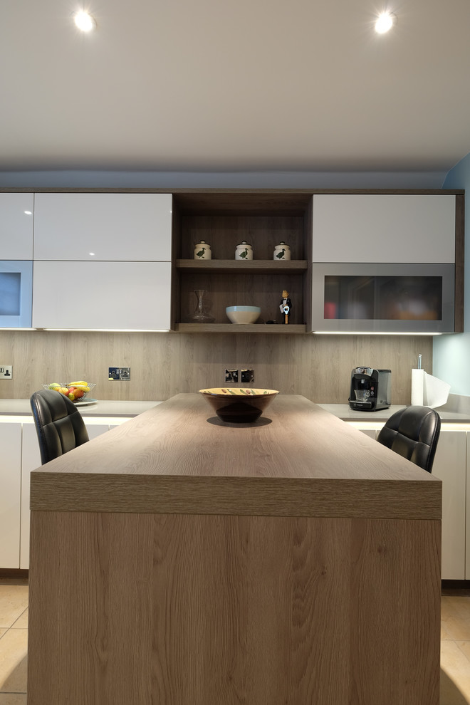 Inspiration for a medium sized modern u-shaped enclosed kitchen in Hampshire with a submerged sink, flat-panel cabinets, white cabinets, quartz worktops, stainless steel appliances, porcelain flooring, a breakfast bar and beige worktops.