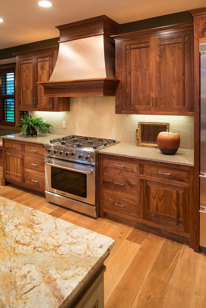 Inspiration for a large craftsman single-wall medium tone wood floor open concept kitchen remodel in Minneapolis with a farmhouse sink, shaker cabinets, dark wood cabinets, granite countertops, beige backsplash, stainless steel appliances and an island
