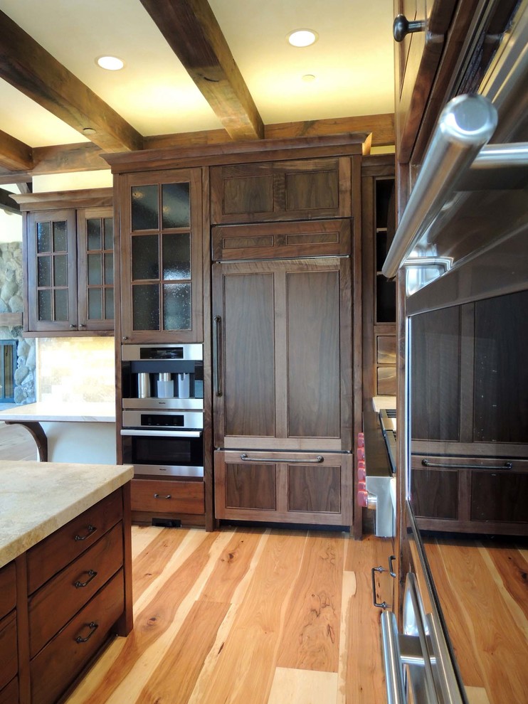 Inspiration for a mid-sized craftsman u-shaped medium tone wood floor eat-in kitchen remodel in Other with dark wood cabinets, marble countertops, multicolored backsplash, stone tile backsplash, an island, a farmhouse sink, recessed-panel cabinets and paneled appliances
