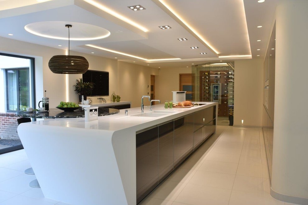 Kitchen - huge modern porcelain tile and white floor kitchen idea in Manchester with an integrated sink, glass-front cabinets, gray cabinets, solid surface countertops, white appliances, an island and white countertops