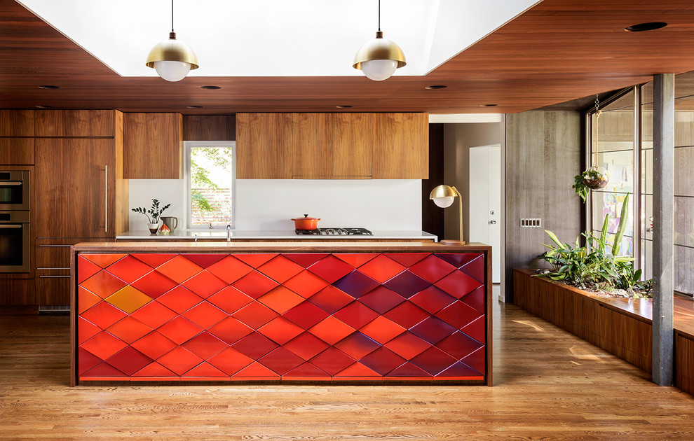 Mid-Century Küche mit flächenbündigen Schrankfronten, Elektrogeräten mit Frontblende, Kücheninsel, hellbraunen Holzschränken, Küchenrückwand in Weiß und braunem Holzboden in Portland