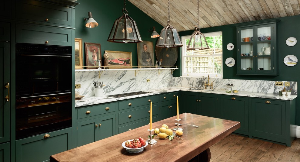 Inspiration for a medium sized traditional l-shaped kitchen/diner in London with a double-bowl sink, shaker cabinets, green cabinets, marble worktops, stone slab splashback, black appliances, light hardwood flooring and no island.