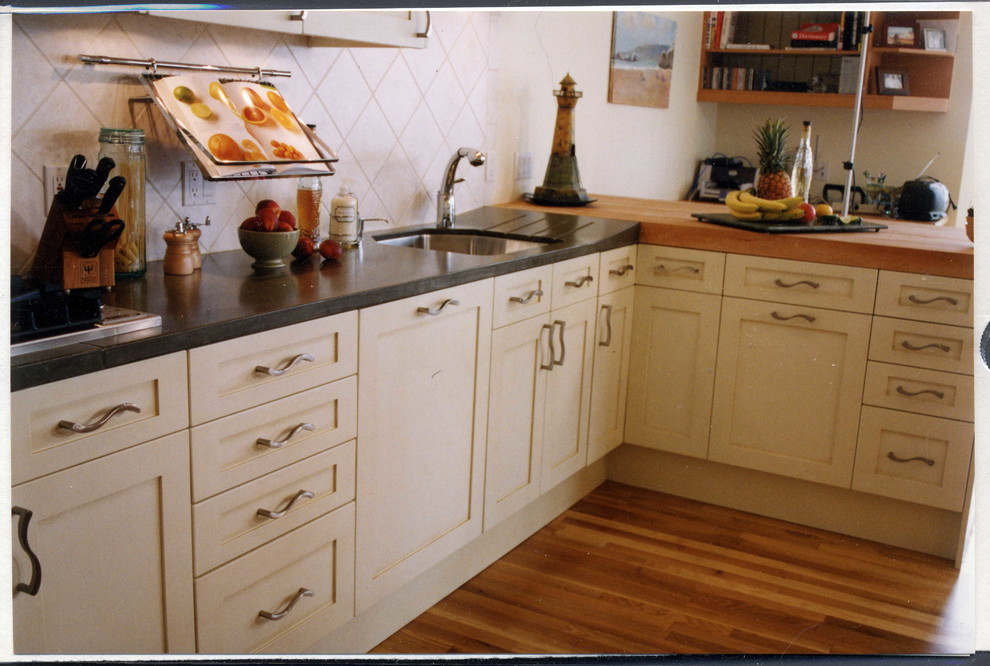 オークランドにある高級な中くらいなトラディショナルスタイルのおしゃれなキッチン (シングルシンク、落し込みパネル扉のキャビネット、白いキャビネット、コンクリートカウンター、白いキッチンパネル、セラミックタイルのキッチンパネル、パネルと同色の調理設備、無垢フローリング、オレンジの床、グレーのキッチンカウンター) の写真