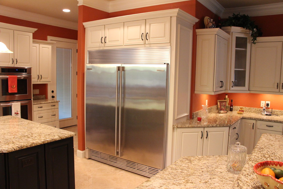 Aménagement d'une cuisine craftsman avec des portes de placard blanches, un plan de travail en granite, une crédence orange et un électroménager en acier inoxydable.