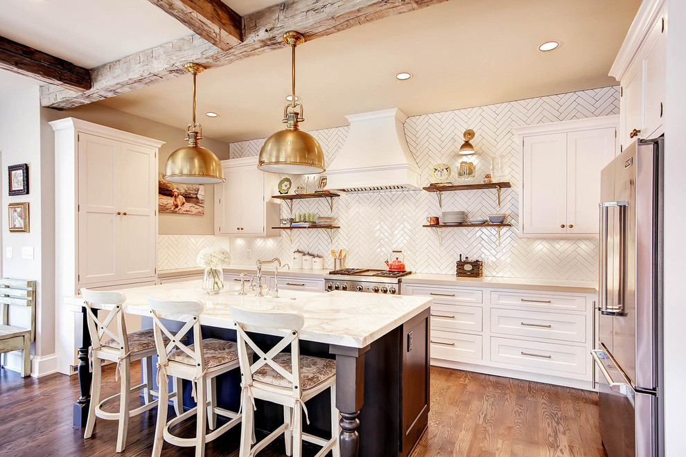 Klassisk inredning av ett kök, med en rustik diskho, luckor med infälld panel, vita skåp, vitt stänkskydd, rostfria vitvaror, mellanmörkt trägolv och en köksö
