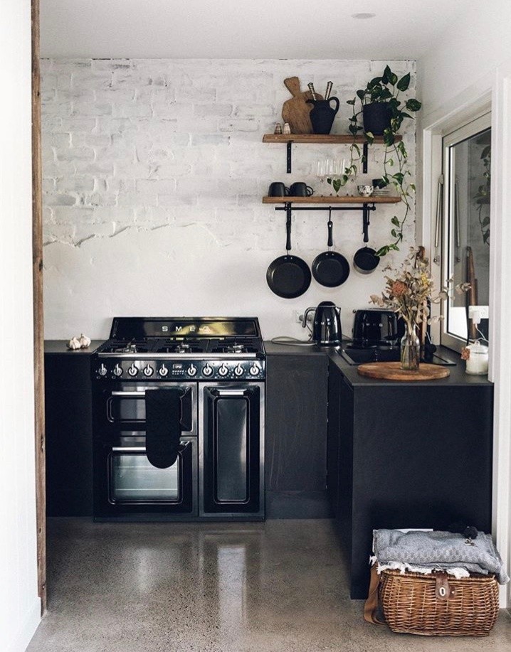 Cette image montre une petite cuisine design en U fermée avec des portes de placard noires et un sol en carrelage de céramique.