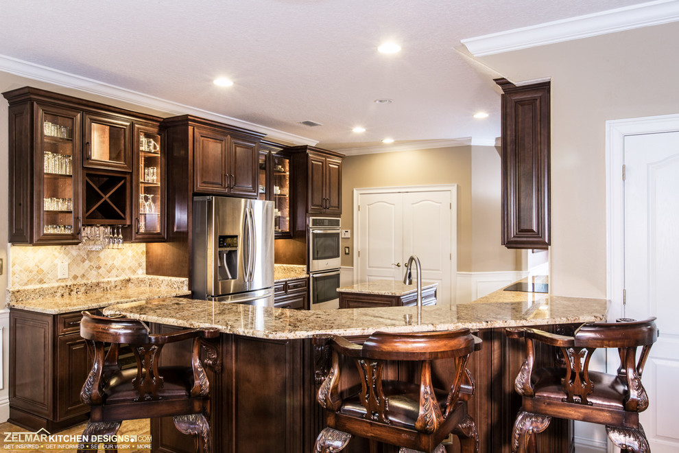 Kitchen pantry - mid-sized traditional u-shaped kitchen pantry idea in Orlando with an undermount sink, raised-panel cabinets, dark wood cabinets, granite countertops, multicolored backsplash, stone tile backsplash and an island