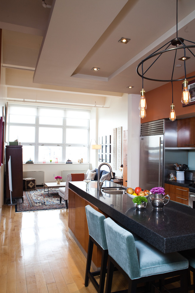 Cette image montre une cuisine ouverte parallèle bohème en bois brun avec un placard à porte plane, un électroménager en acier inoxydable et un évier 2 bacs.