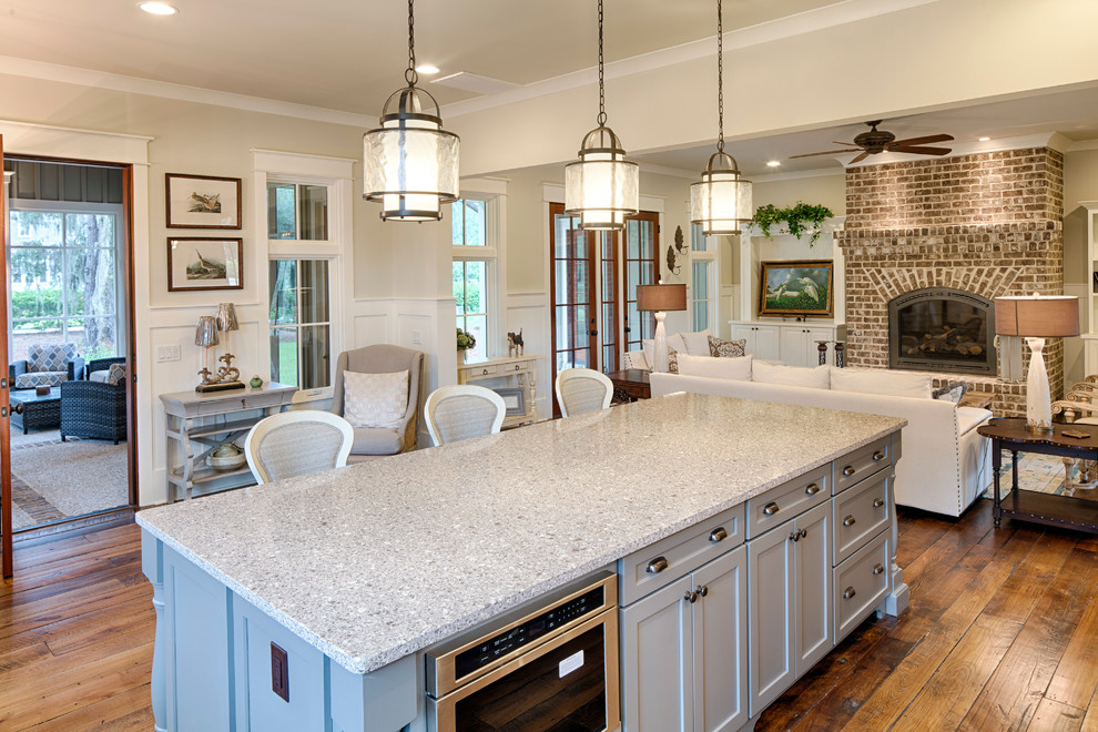 Inspiration for a medium sized traditional l-shaped kitchen/diner in Charleston with a belfast sink, recessed-panel cabinets, white cabinets, engineered stone countertops, white splashback, metro tiled splashback, stainless steel appliances, medium hardwood flooring and an island.