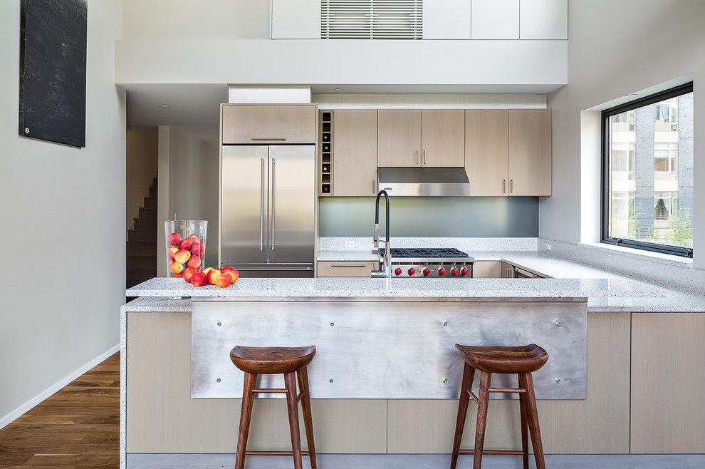 Moderne Küche in U-Form mit flächenbündigen Schrankfronten, hellen Holzschränken, Küchengeräten aus Edelstahl, braunem Holzboden und Halbinsel in New York