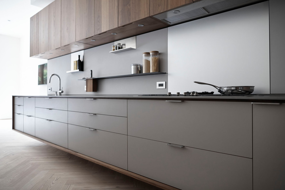 Eat-in kitchen - mid-sized modern l-shaped eat-in kitchen idea in New York with an undermount sink, flat-panel cabinets, medium tone wood cabinets, solid surface countertops, gray backsplash, stainless steel appliances, an island and gray countertops