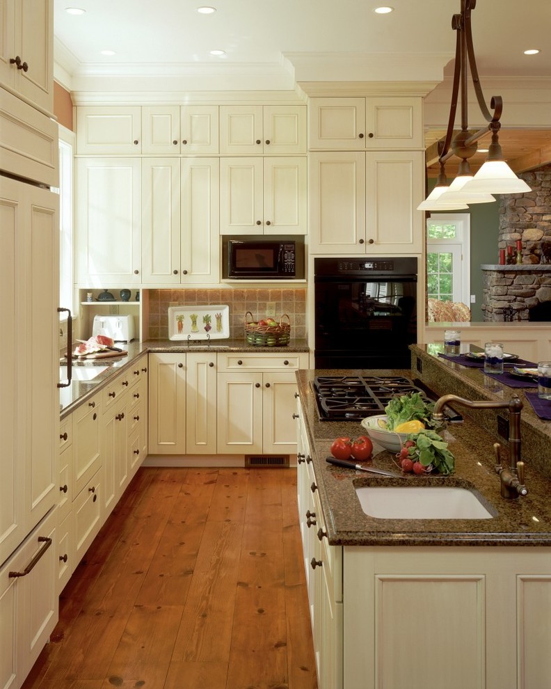 Bild på ett vintage kök med öppen planlösning, med en undermonterad diskho, luckor med infälld panel, beige skåp, beige stänkskydd, mellanmörkt trägolv och en köksö