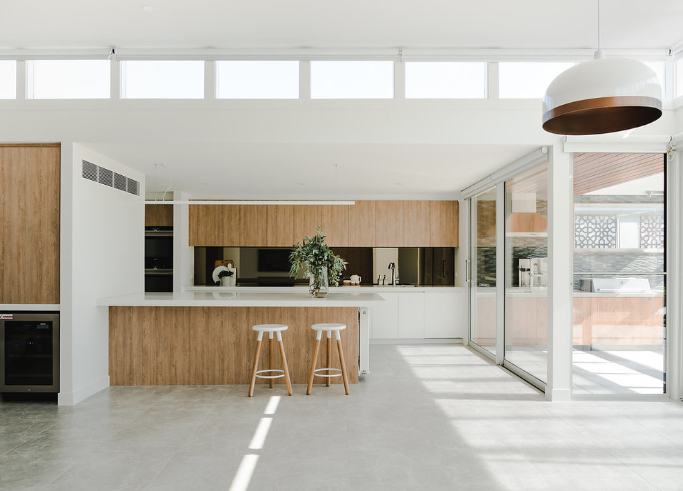 Design ideas for a contemporary kitchen in Melbourne with a submerged sink, engineered stone countertops, metallic splashback, mirror splashback, stainless steel appliances, porcelain flooring, an island, grey floors and white worktops.