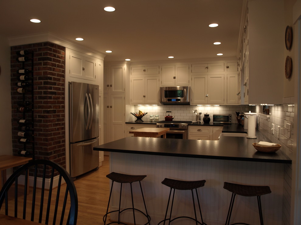 Eat-in kitchen - mid-sized farmhouse u-shaped light wood floor eat-in kitchen idea in Newark with a farmhouse sink, shaker cabinets, white cabinets, soapstone countertops, white backsplash, subway tile backsplash and stainless steel appliances