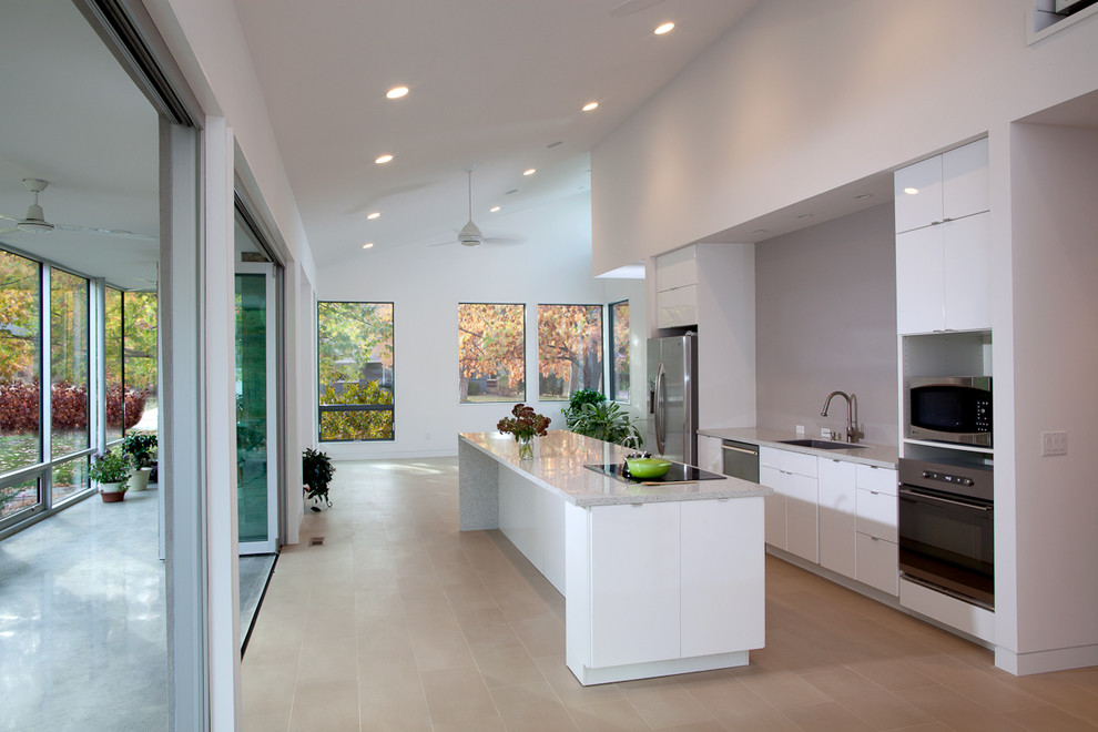 Diseño de cocina moderna con armarios con paneles lisos, puertas de armario blancas, salpicadero verde y electrodomésticos de acero inoxidable