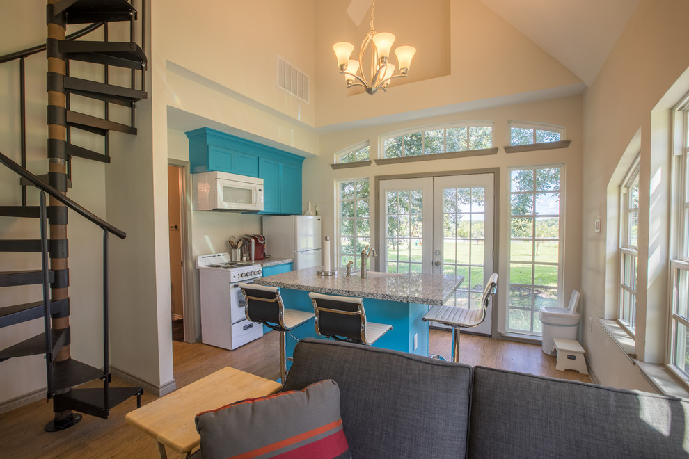Bild på ett litet minimalistiskt linjärt kök med öppen planlösning, med blå skåp, en köksö, luckor med infälld panel, en rustik diskho, granitbänkskiva, vita vitvaror, mellanmörkt trägolv och brunt golv