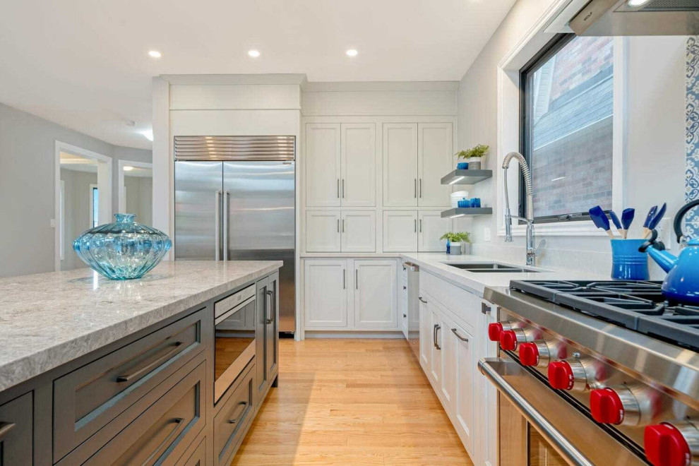 Inspiration for a large traditional l-shaped kitchen/diner in Toronto with a submerged sink, shaker cabinets, white cabinets, engineered stone countertops, blue splashback, mosaic tiled splashback, stainless steel appliances, light hardwood flooring, an island, yellow floors and grey worktops.