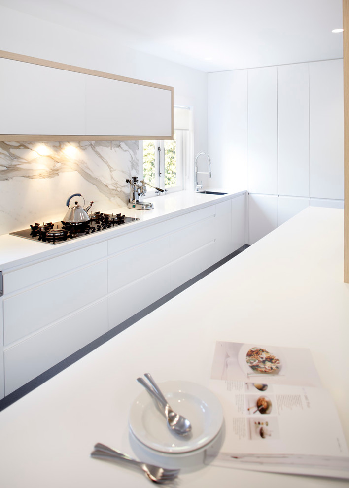 Modern inredning av ett linjärt kök och matrum, med en nedsänkt diskho, släta luckor, vita skåp, bänkskiva i koppar, stänkskydd i sten och rostfria vitvaror