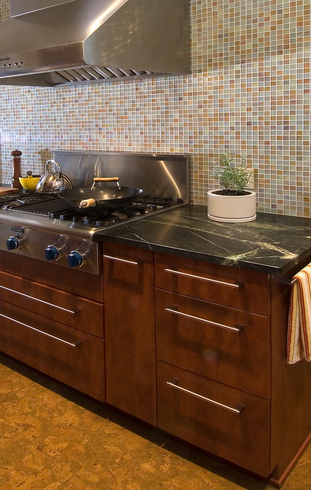 Exempel på ett modernt kök, med en undermonterad diskho, släta luckor, skåp i mellenmörkt trä, bänkskiva i täljsten, flerfärgad stänkskydd, glaspanel som stänkskydd, rostfria vitvaror och korkgolv