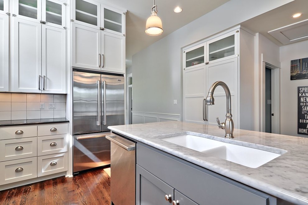 オースティンにあるトランジショナルスタイルのおしゃれなキッチン (ダブルシンク、落し込みパネル扉のキャビネット、白いキッチンパネル、シルバーの調理設備) の写真