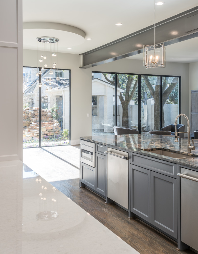 Inspiration for a large transitional l-shaped medium tone wood floor and brown floor eat-in kitchen remodel in Dallas with an undermount sink, shaker cabinets, gray cabinets, quartzite countertops, white backsplash, glass tile backsplash, stainless steel appliances and an island
