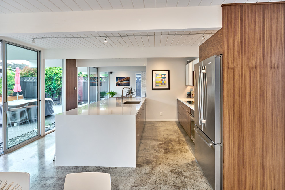 Photo of a contemporary kitchen in San Francisco with a single-bowl sink, flat-panel cabinets, engineered stone countertops, metro tiled splashback, stainless steel appliances and concrete flooring.