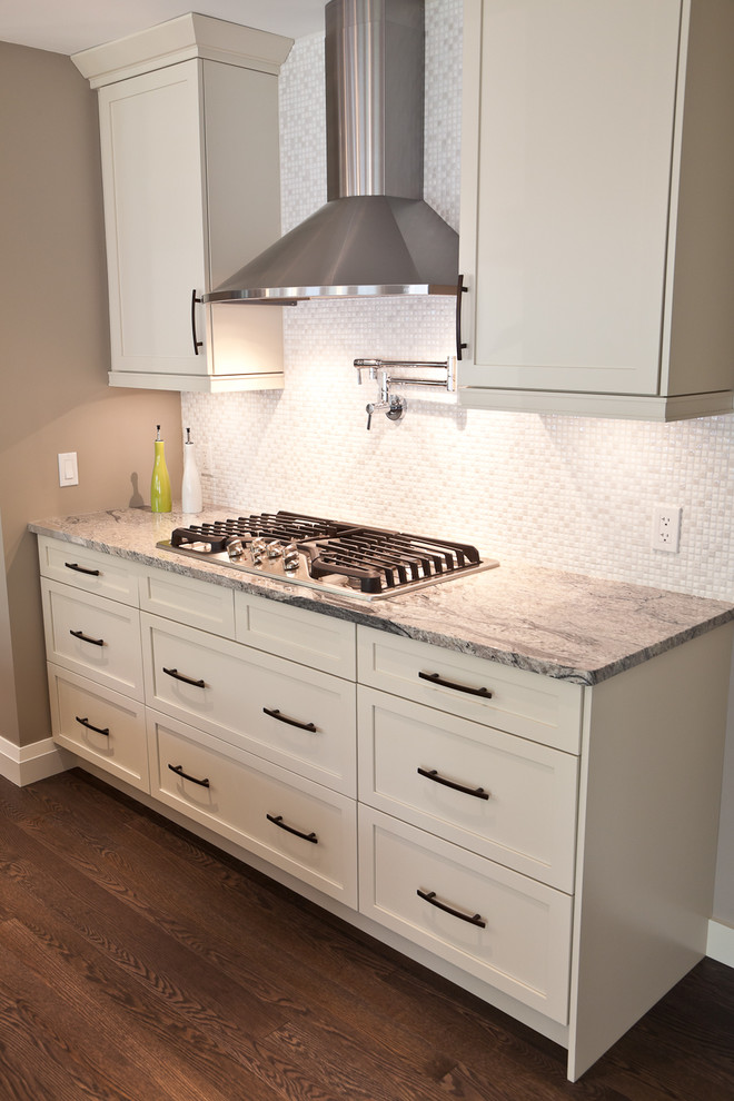 Kitchen - large transitional galley dark wood floor kitchen idea in Calgary with a single-bowl sink, shaker cabinets, white cabinets, granite countertops, white backsplash, mosaic tile backsplash, stainless steel appliances and an island