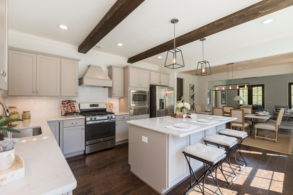 Example of a mid-sized transitional l-shaped dark wood floor open concept kitchen design in Birmingham with a single-bowl sink, shaker cabinets, gray cabinets, marble countertops, white backsplash, subway tile backsplash, stainless steel appliances and an island