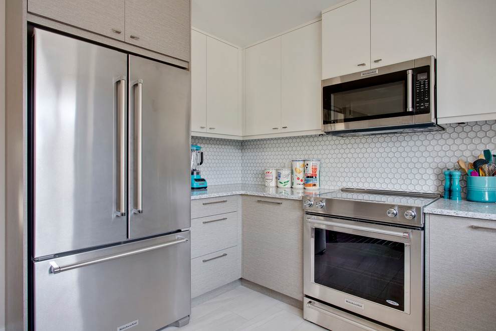 Modern inredning av ett u-kök, med en undermonterad diskho, släta luckor, grå skåp, granitbänkskiva, grått stänkskydd, stänkskydd i mosaik, rostfria vitvaror, klinkergolv i porslin och en halv köksö